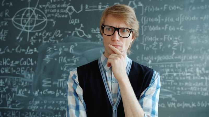 A student stands before a chalkboard full of formulas, focused on problem solving for math and physics students