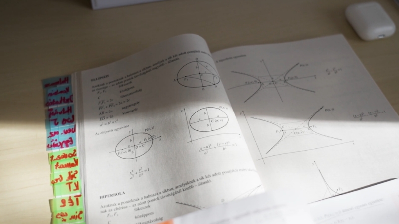 An open textbook with math diagrams and handwritten notes, typical of focused study in STEM education
