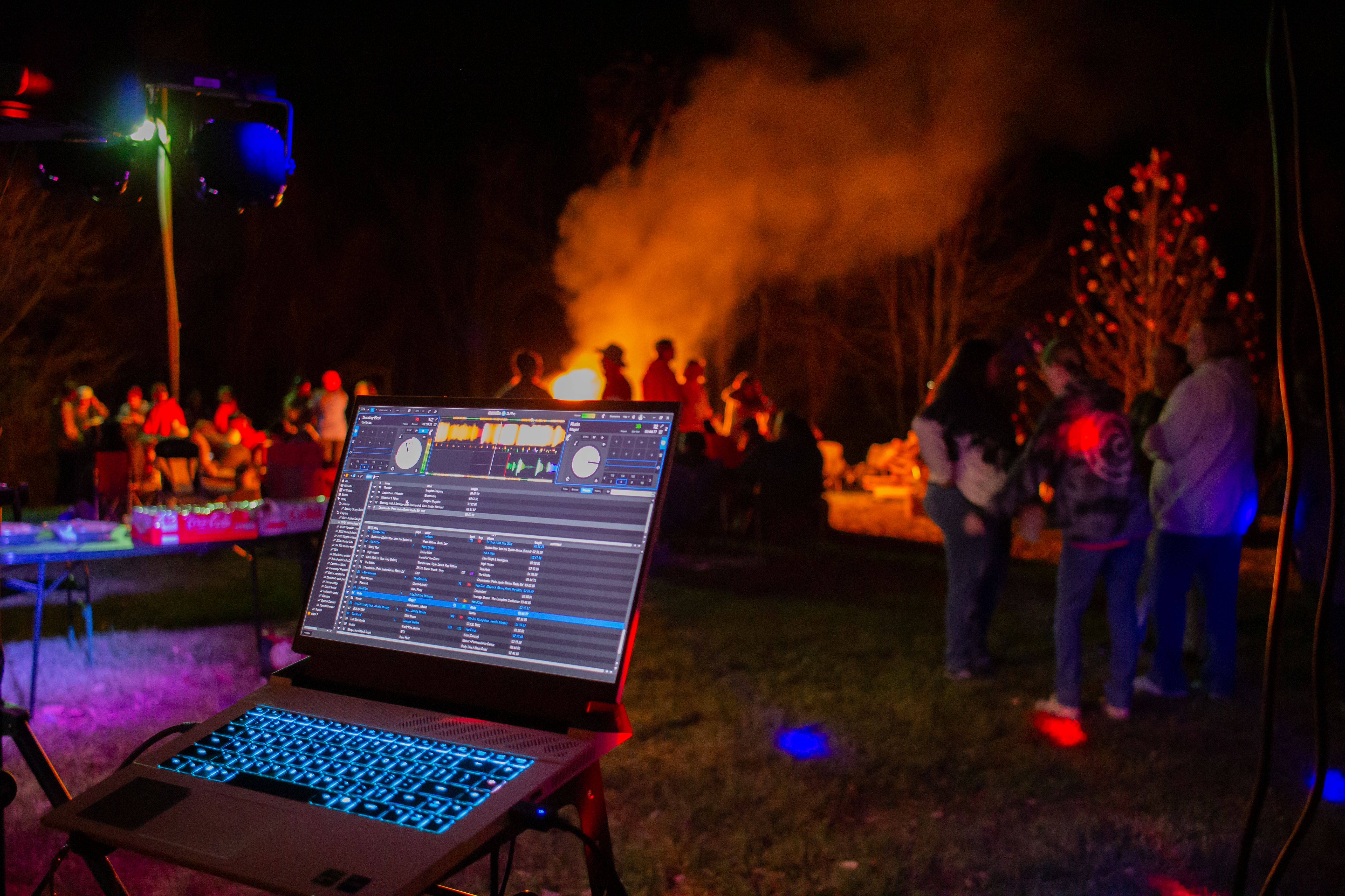 Outdoor night party with a DJ setup and blazing bonfire